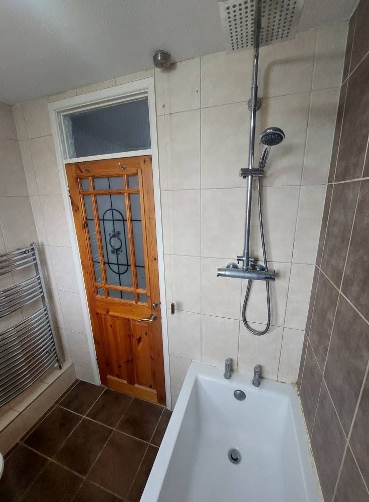 Shower over bath with brown floor tiles